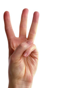 An adult female hand holding three fingers in the air spread apart, (with clipping path)